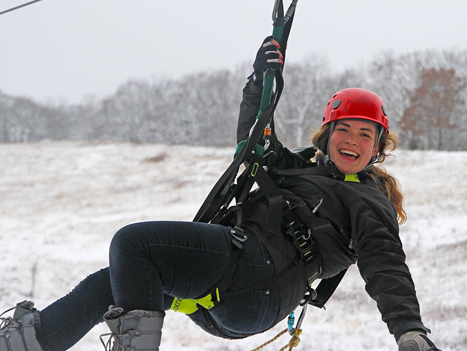 Woman smiling and ziplining in the snow