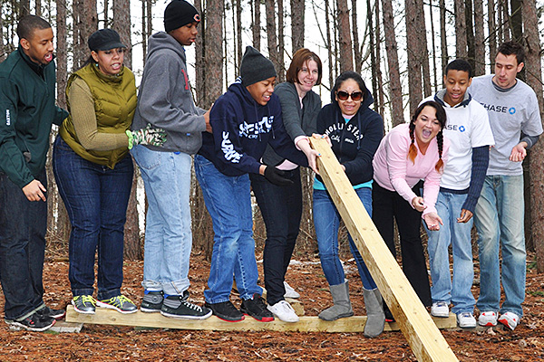 Group of people lifting a wooden beam